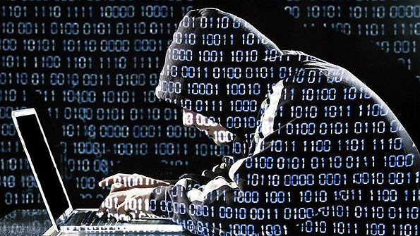 A hooded hacker uses his skills to stea wreak havoc or cause harm