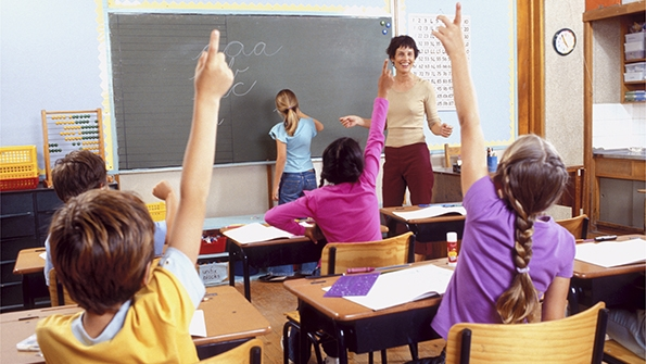 Elementary students raising hands in classroom