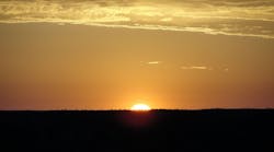 The sun rising over the Australian Desert. The cool of the night was about to vanish in a wave of heat as the brightening light washed over the desert and Ayers Rock.