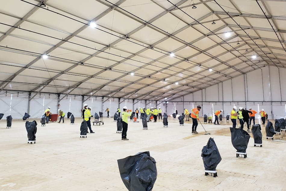 Workers prepare the flooring inside a climate-controlled tent under construction at SUNY, Stony Brook.