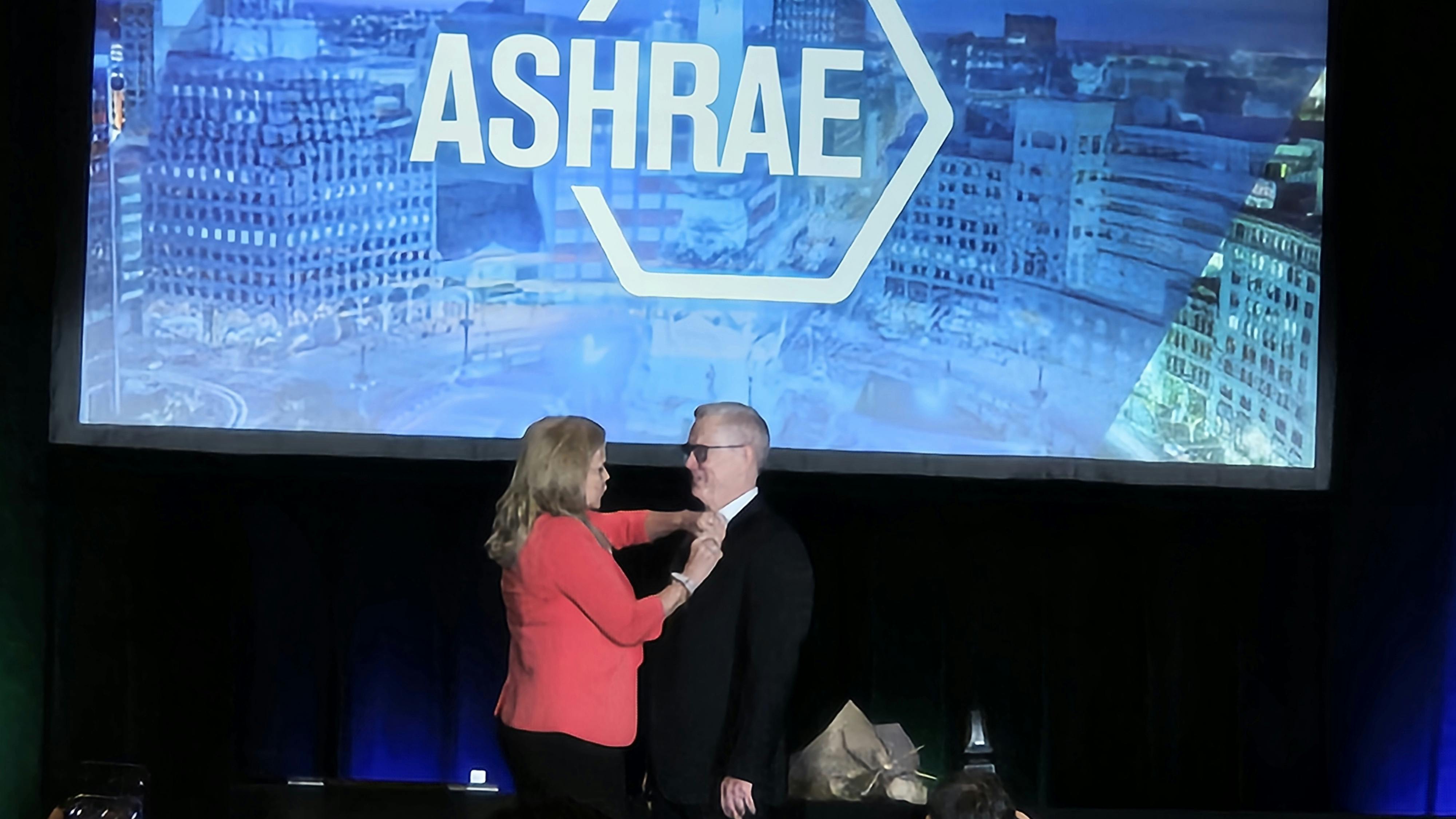 PASSING THE TORCH: Outgoing ASHRAE President Ginger Scoggins last week transferred the Presidential pin to her successor, Dennis Knight.